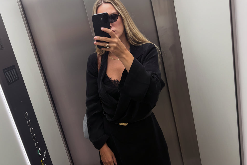 Czarna krótka sukienka kopertowa z długim rękawem w stylizacji z czarnymi dodatkami – ujęcie lifestyle.
